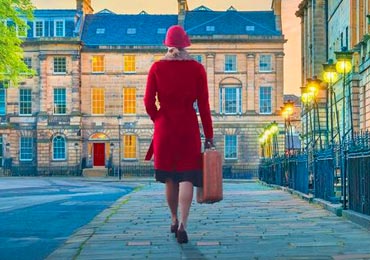 A woman in a red coat walking toward a building